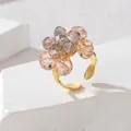 Detail eines Perlenblumenrings mit champagnerfarbenen Kristallen und Goldband - Rosa-Grau