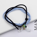 Detail of woven astronaut couple bracelets with star and planet charms in black and blue - Blue And Black
