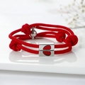 Red braided couple bracelets with silver magnetic heart clasp on white background - Red