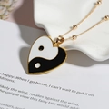Dettaglio di un ciondolo yin yang a forma di cuore con catena a sfere dorate su bianco - Cuore (Yin Yang Nero E Bianco)