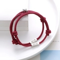 Detail of reddish-brown woven couple bracelets with custom engraved charms and magnetic bells - Burgundy