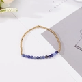 Pulsera minimalista de cuentas doradas y piedra natural azul para parejas sobre fondo blanco - Lapislázuli