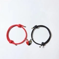 Red and black woven couple bracelets with magnetic heart-shaped pendants on white background - Black And Red Cord With Black And Red Heart