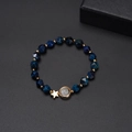 Blue faceted bead bracelet with golden star and moon charms on a black background - Blue Beaded Planet Pendant Style / Blue/Gold