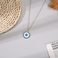 Dettaglio della collana con ciondolo occhio greco dorato e smalto blu su sfondo naturale - Tondo Blu Catena d'Oro