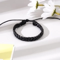Detail of black braided leather bracelet with adjustable cord on white background - Cross Woven Style