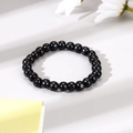 Bracciale da uomo con perle nere lucide effetto ossidiana su superficie bianca pulita - Stile con Perline Nere / Nero