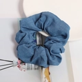 Chic blue denim hair scrunchie with pleated fabric texture displayed on a white plate - Solid Denim Blue