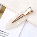 Pearlescent white acetate hair clip with golden metal clip on minimalist background - Beige