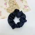 Gros plan d'un chouchou en satin noir avec texture lisse et bande élastique interne - Noir
