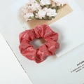 Detail of red glitter fabric scrunchie on a magazine with pink carnation accents - Red
