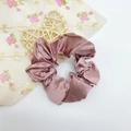 Détail macro du chouchou en satin de soie rose poudré avec texture plissée et éclat - Marron