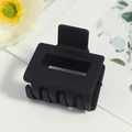 Pince à cheveux rectangulaire noir mat au design épuré sur une surface blanche - Noir mat