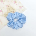 Chouchou en satin bleu ciel brillant avec texture soyeuse sur fond de dentelle - Bleu ciel