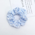 Light blue floral scrunchie with pleated texture shown on a minimalist white backdrop - Blue