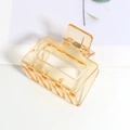 Gros plan détaillé d'une pince à cheveux rectangulaire ambre mat avec ressort doré - Orange Transparent