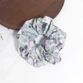 Nahaufnahme eines großen Scrunchies mit Ölgemälde-Blumenmuster in Hellblau und Grün - Grau