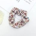 Detailed macro view of white floral fabric scrunchie with red and blue flower patterns - Red Blue Floral