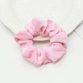 Chouchou en velours rose brillant posé sur une assiette élégante en céramique blanche - Rose