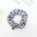 Detailed macro view of white fabric scrunchie with blue and brown floral patterns - Blue Caramel Floral