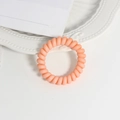 Nahaufnahme eines matten orangefarbenen Spiralhaargummis auf weißem Keramikteller - Farbe 9
