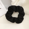 Close-up of black knitted scrunchie with soft yarn texture and elastic wavy design - Black