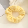 Close-up of light yellow knitted scrunchie showing detailed hollow weave texture and fabric - Yellow