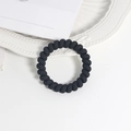 Close-up of black matte spiral hair tie on a white elegant decorative plate - Color 4