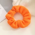 Close-up of bright orange knitted scrunchie showing detailed ribbed texture and elastic band - Orange