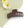Gros plan d'une grande pince à cheveux marron mat avec dents imbriquées sur fond vert - No.4 Brun Foncé