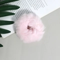 Gedetailleerde close-up van een roze pluche scrunchie op een decoratieve achtergrond - Roze
