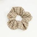 Detailed close-up of brown houndstooth fabric scrunchie hair tie on white background - Beige