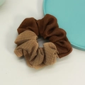 Dettaglio di un elegante scrunchie bicolore in twill marrone e tessuto a quadri oro champagne - Marrone