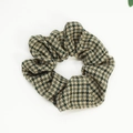 Close-up of houndstooth fabric hair scrunchie showing fine textile texture and elastic design - Green