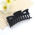 Dettaglio macro della grande molletta per capelli nera opaca con design a più denti - Design a Croce Classico Grande