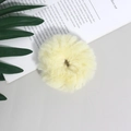 Dettaglio di un elastico per capelli in peluche giallo pallido su sfondo minimalista - Giallo chiaro