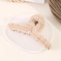 Vue macro d'une grande pince à cheveux en fausse fourrure beige sur une assiette blanche - Khaki