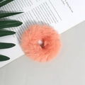 Dettaglio di un elastico per capelli in pelliccia sintetica color pesca su un libro - Arancione