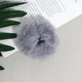 Dettaglio di un elastico per capelli in finta pelliccia grigio chiaro su un libro - Grigio