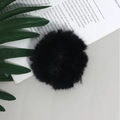 Dettaglio di un morbido elastico per capelli in finta pelliccia nera su fondo moderno - Nero