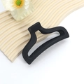 Close-up of a matte black large geometric hair claw clip on a minimalist white surface - Simple Geometric Hollow Style
