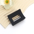 Detailed close-up of a matte black rectangular hair claw clip on a decorative background - Minimalist Rectangular Style