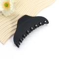 Close-up of matte black hair claw clip with strong grip teeth on aesthetic backdrop - Elegant Curved Style