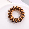 Detail of spiral telephone cord hair tie with orange and coffee brown color contrast - Yellow Coffee Black