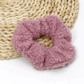Detail view of pink lamb wool hair scrunchie with soft fluffy texture on a woven mat - Rose Red