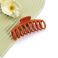 Détail d'une grande pince à cheveux orange mat sur un plateau avec une fleur blanche - No.32 Orange Mat