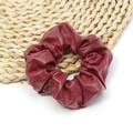 Close-up of wine red faux leather hair scrunchie with soft pleated texture on woven mat - Burgundy