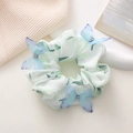 Détail d'un chouchou vert clair avec des papillons 3D bleus et des strass étincelants - vert clair