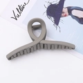 Détail de la pince à cheveux taupe mate avec design torsadé et longues dents sur magazine - Style Torsadé Croisé / Gris
