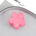 Detailed macro view of a matte pink flower-shaped hair claw clip on a gray tray - Red